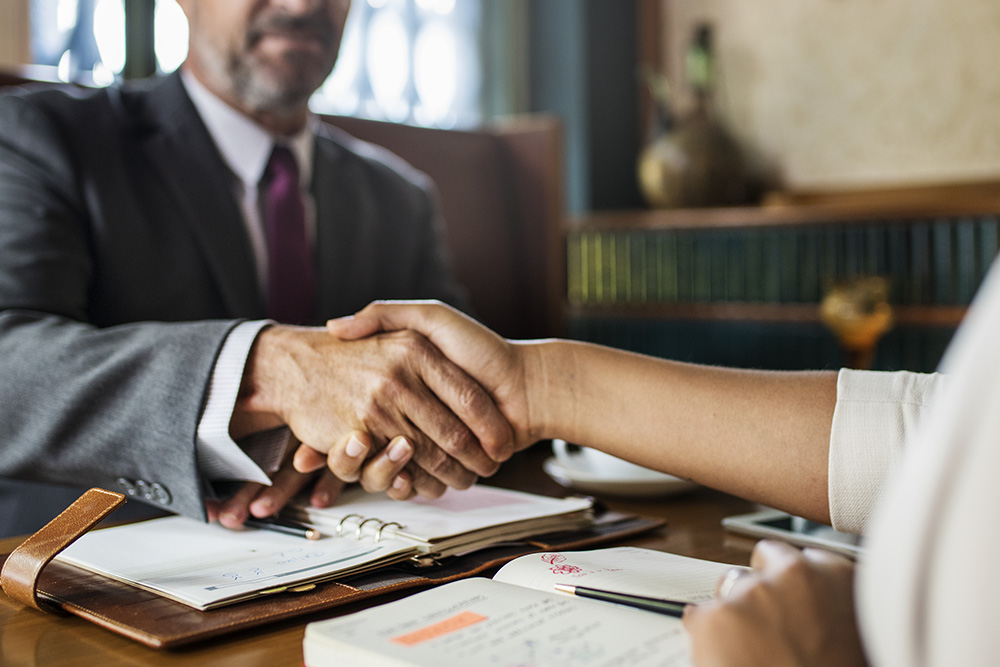 Profissionais da Mira Recuperadora de Créditos apertando a mão do cliente, simbolizando um contrato fechado com a empresa que teve resultados com os recebíveis.